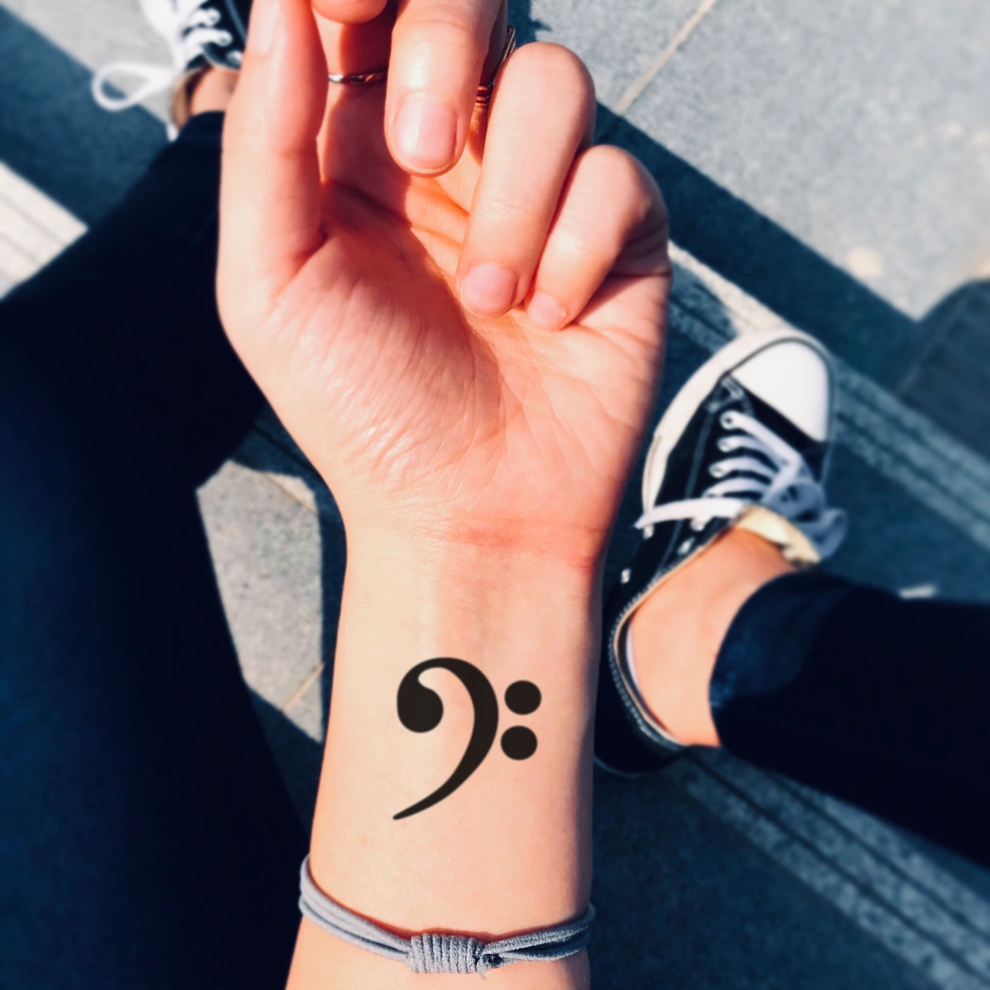 fake small bass clef music temporary tattoo sticker design idea on wrist